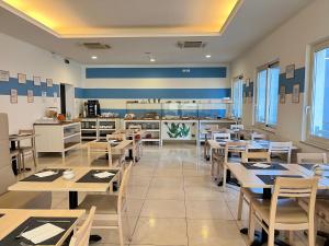restauracja z drewnianymi stołami i krzesłami oraz kuchnią w obiekcie Hotel Berenice w Rimini