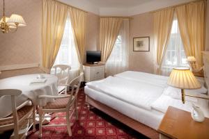 Una habitación de hotel con una cama, una mesa y un escritorio. en Alpská růže, en Luhačovice