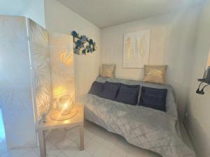 a bedroom with a bed and a table with a lamp at Fréjus Plage Paradis T1 cabine clim terrasse Wi-Fi in Fréjus