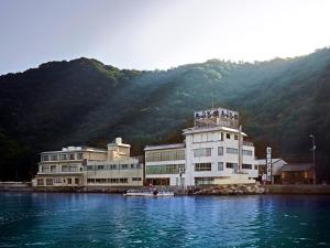 a large building on the water next to a mountain at Abuto Honkan in Fukuyama