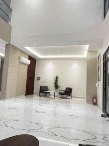 an empty lobby with two chairs and a plant at قصر أباهي للوحدات السكنية المفروشة in Al Kharj
