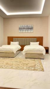 two beds in a large room with at قصر أباهي للوحدات السكنية المفروشة in Al Kharj