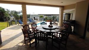eine Terrasse mit Tisch und Stühlen und einem Pool in der Unterkunft The Royal Familia Beach House in Zinkwazi Beach
