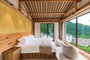 una camera da letto con un letto grande e una grande finestra di 问安民宿（黄山风景区店） a Mount Huangshan