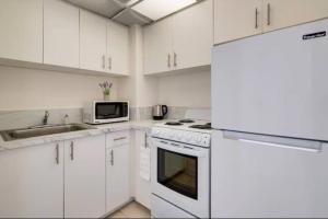 a white kitchen with white cabinets and a microwave at Scenic 1BR 1BA Retreat with Amazing Views in Miami Beach