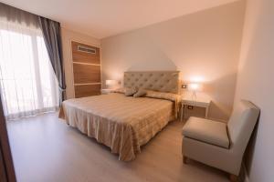 a bedroom with a bed and a chair and a window at Hotel Mirasole International in Gaeta