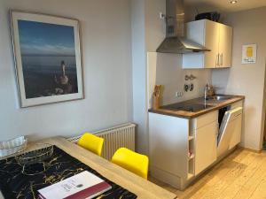 a kitchen with a table and a sink and a kitchen with yellow chairs at Seeblick - Chice Maisonette über den Dächern von Meersburg in Meersburg