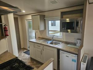 a small kitchen with a sink and a microwave at Beachside Holiday Park in Brean +10 photos