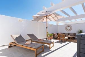 a patio with two chairs and an umbrella at Luxury apartment with sunny roof terrace - Sonrisa in Estepona