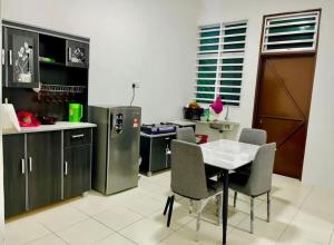 a kitchen with a table and chairs and a refrigerator at Homestay Jannah Changlun in Changlun