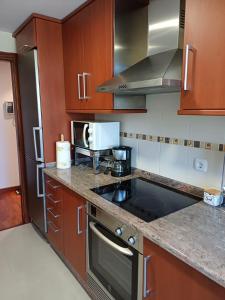 a kitchen with wooden cabinets and a stove top oven at Mar de Covelo in Pontevedra +21 photos