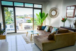 een woonkamer met een bank en een groot raam bij Apt au calme proche mer terrasse in Flic-en-Flac