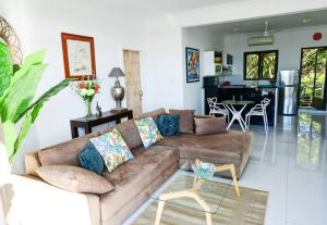 een woonkamer met een bruine bank en een keuken bij Apt au calme proche mer terrasse in Flic-en-Flac