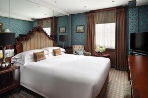 a bedroom with a large white bed and a television at The Chesterfield Mayfair in London