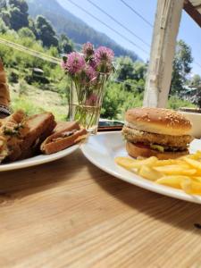 two plates with a sandwich and french fries on a table at The Satvic Retreat in Manāli