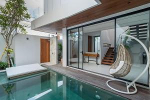 ein Haus mit einem Pool mit einem Stuhl daneben in der Unterkunft Luxury Haven Stunning 2Br in Umalas Canggu in Kerobokan