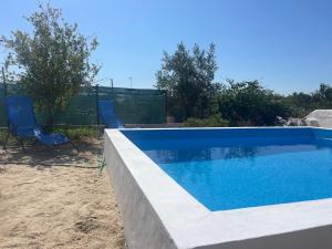a swimming pool with two blue chairs next to it at Casa da Barragem Montargil in Montargil