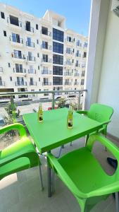 una mesa verde y sillas en un balcón con un edificio en Frida Luxury Beach Apartment, en Lezhë