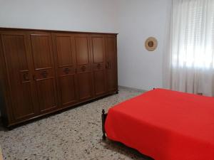 a bedroom with a red bed and wooden cabinets at Flavia House in Ladispoli