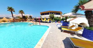 a pool with chairs and umbrellas next to a resort at Nirvana Club Village in Botricello