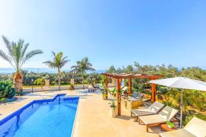 - une piscine avec des chaises et un parasol à côté de la piscine dans l'établissement Petrides Villa, à Argaka