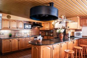 une grande cuisine avec des armoires en bois et un plafond noir dans l'établissement Espacio de paz, ideal para familias Villa Amalia, à Llacuna