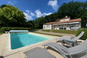 a swimming pool with chairs and a house at La Terrasse in Douzillac