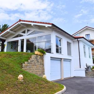 a white house with two garage doors at Playa Joyel Family Surf House in Noja