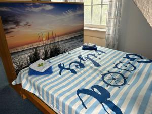 a bed with a blue and white striped bedspread with the word beach at Friesenrose Süd in Spiekeroog