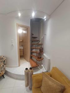 a living room with a couch and a spiral staircase at Μονοκατοικία «Maizonette passaggio G» in Volos