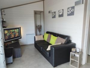 a black leather couch in a living room with a tv at Chalet in Hudimesnil