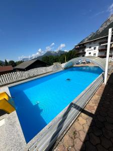 a large blue swimming pool on top of a building at Landhaus Alpenblick in Obsteig