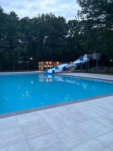 a blue swimming pool with a water slide at Chalet de kleine Eekhoorn in Lage Mierde