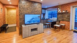 a living room with a flat screen tv on a stone wall at SunCity Apartment in Šiauliai +6 photos