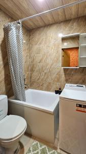 a bathroom with a tub and a toilet and a sink at SunCity Apartment in Šiauliai