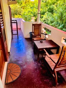 a balcony with two chairs and a wooden table at Deshan Homestay & Restaurant in Tangalle