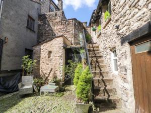 un vieux bâtiment en pierre avec un escalier dans une cour dans l'établissement The Landings, à Kirkby Lonsdale