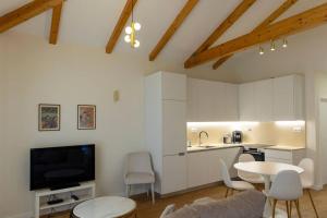a kitchen with white cabinets and a table and a tv at Casa Galvão Arcos de Valdevez in Arcos de Valdevez