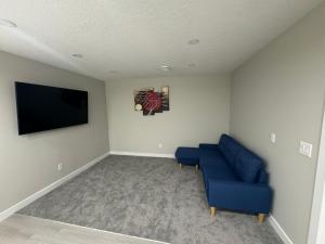 ein Wohnzimmer mit einem blauen Sofa und einem Flachbild-TV in der Unterkunft Cozy 1 bedroom basement apartment in Airdrie