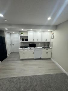 eine leere Küche mit weißen Schränken und einem Waschbecken in der Unterkunft Cozy 1 bedroom basement apartment in Airdrie