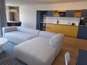 a living room with a white couch and a kitchen at Apartman Plesa in Povljana