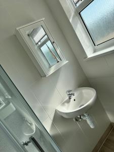 a white bathroom with a sink and a window at Tranquility at Sandown Bay in Sandown +16 photos
