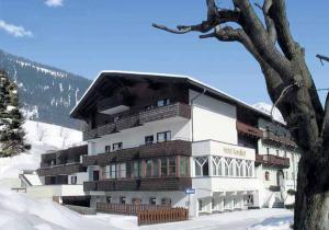duży budynek w śniegu obok drzewa w obiekcie Langley Hotel Rendlhof w mieście Sankt Anton am Arlberg