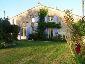 ein großes Steinhaus mit einem grünen Hof in der Unterkunft Chambres d'hôtes entre Niort et Marais Poitevin in Bessines