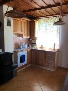 a kitchen with wooden cabinets and a stove and a window at Viola Apartman in Zamárdi