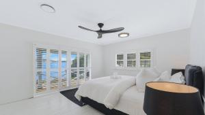 ein weißes Schlafzimmer mit Bett und Deckenventilator in der Unterkunft 'Yaringaa' by HolidayCo in Hardys Bay