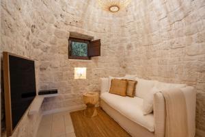 a living room with a white couch and a stone wall at Trullo Perla Greta - Luxury Country Villa & private heated pool in Alberobello