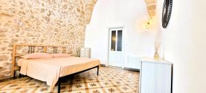 a bedroom with a bed and a stone wall at Villa Pestanaca in Tiggiano