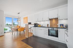 eine Küche mit weißen Schränken und einem Esstisch in der Unterkunft Heimathafen mit See- & Bergsicht in Friedrichshafen + 12 Fotos