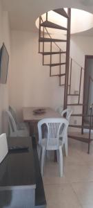 a living room with a table and chairs and a spiral staircase at Praias do Sul in Cabo Frio